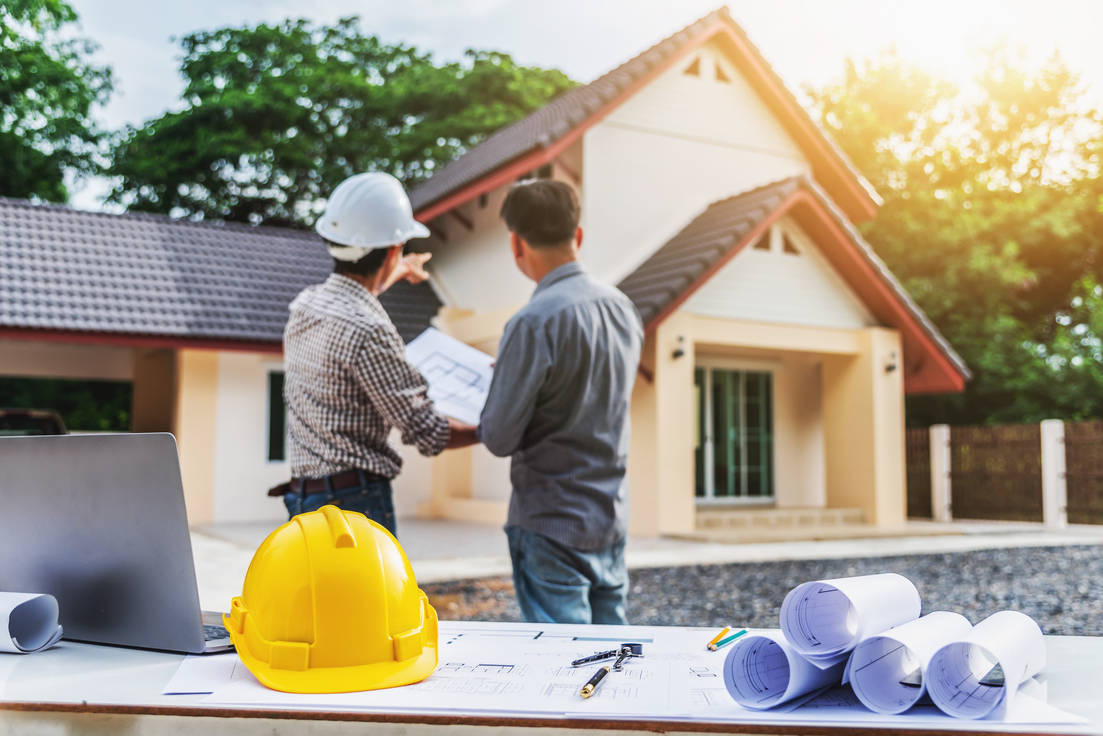 Inspector reviewing plans with homeowner outside of a house