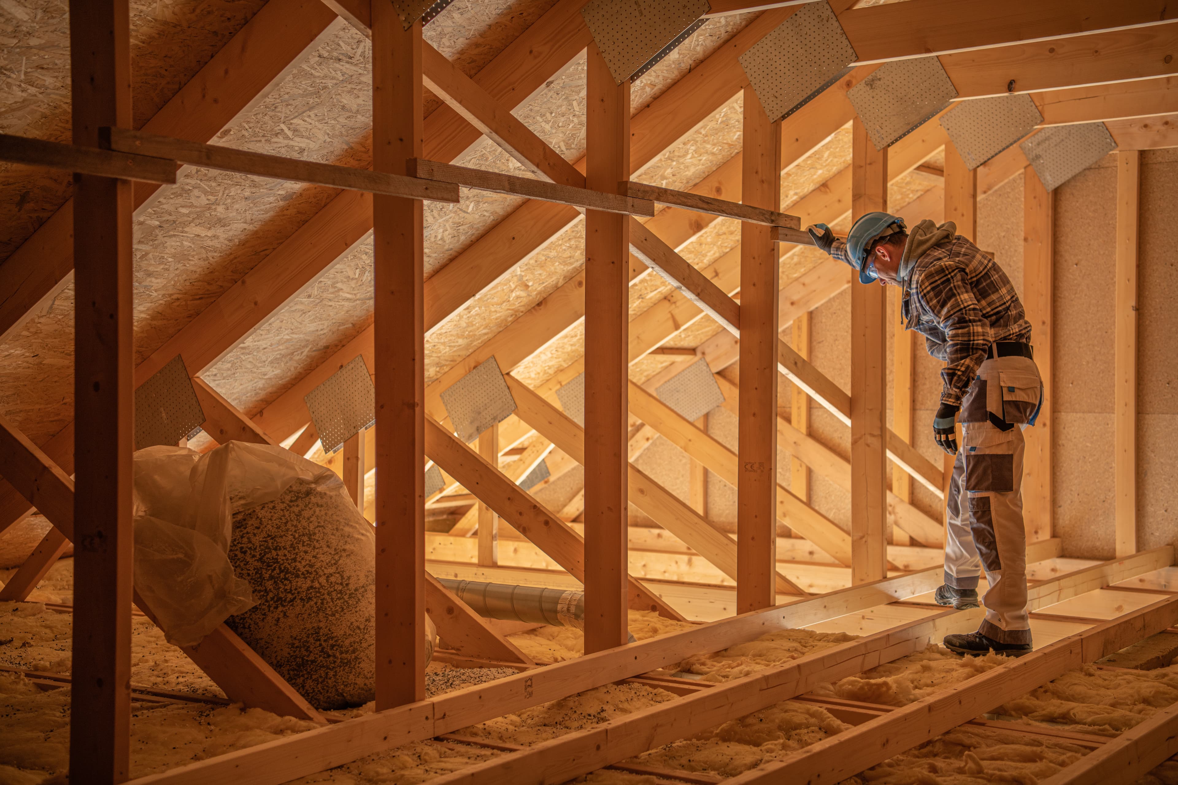 Inspector reviewing equipment while walking through an attic