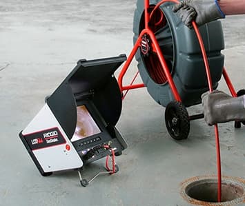 Technician operating a sewer scope inspection camera and reel